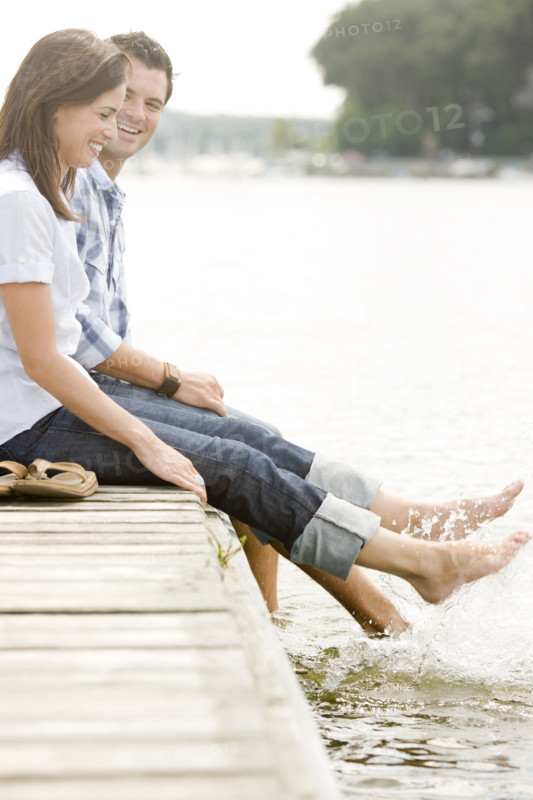 Couple sitting on dock and splashing feet in lake. Date : 2008