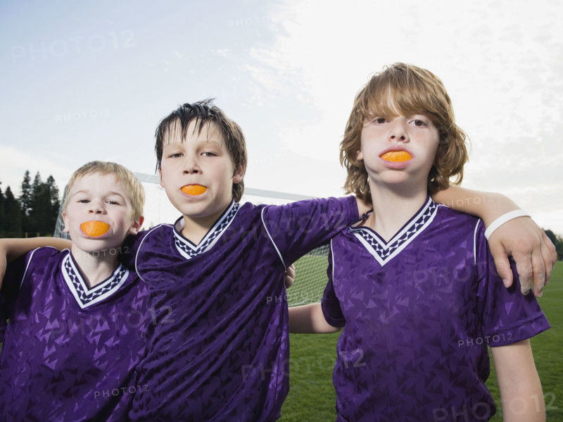 Portrait of boys in soccer uniforms with orange wedges in mouth. Date: 2008