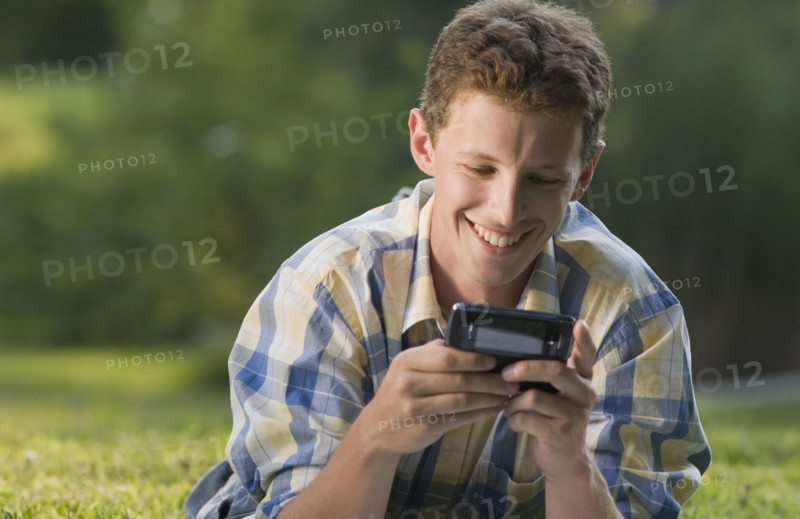 Man laying in grass and text messaging. Date : 2008