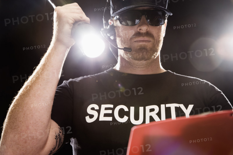 Bouncer looking at guest list with flashlight. Date: 2008