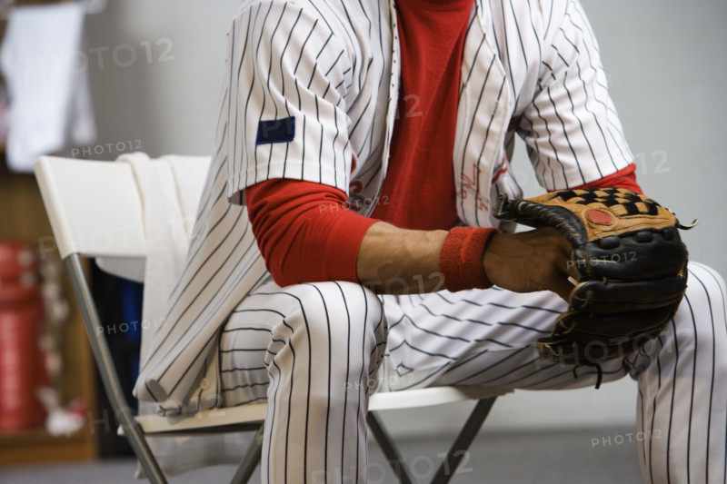 Baseball player holding glove in locker room. Date: 2008