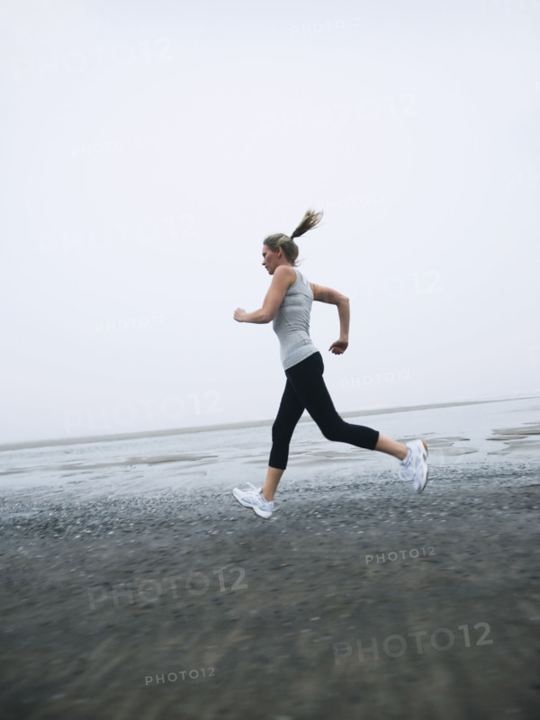 Woman jogging on foggy beach. Date : 2008