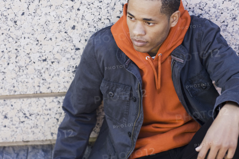 Man sitting against wall looking worried. Date : 2008