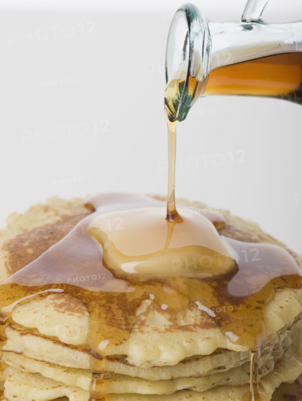 Close up of maple syrup being poured on pancakes.