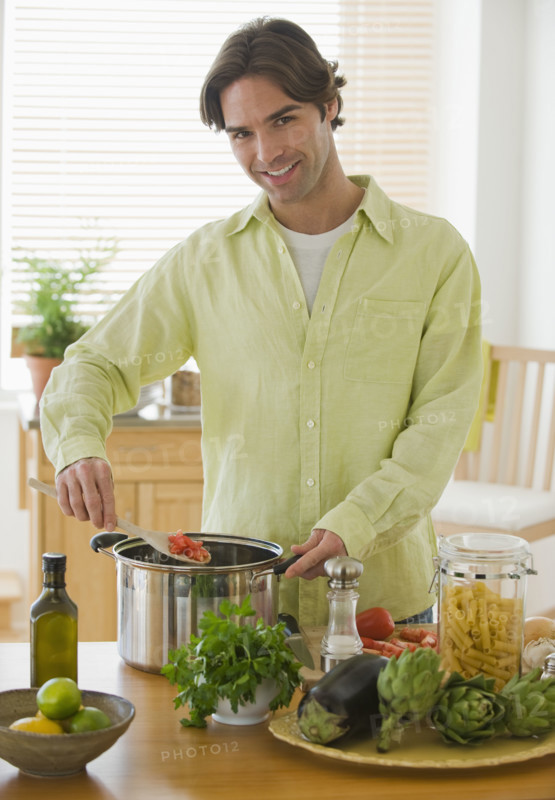 Portrait of man preparing meal in kitchen.