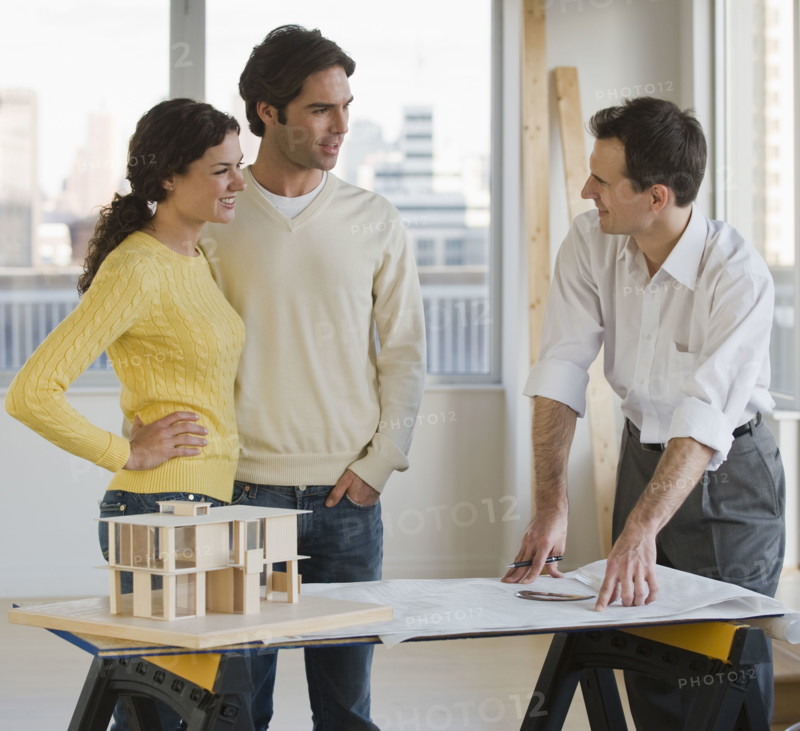 Architect presenting blueprints to couple.