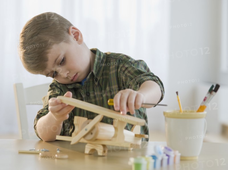 Boy building wooden airplane model.