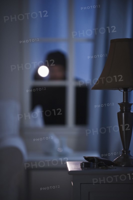 Burglar looking in house window.