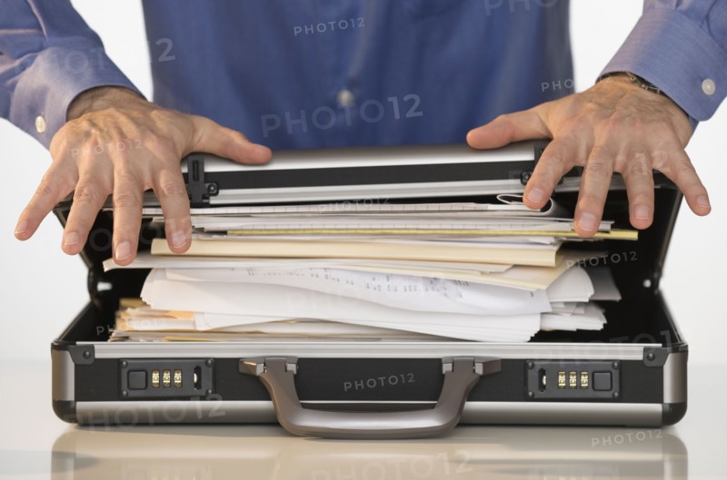 Businessman trying to close briefcase.
