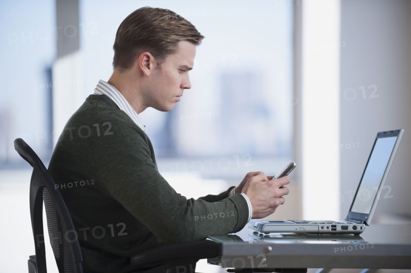 Businessman text messaging in office.