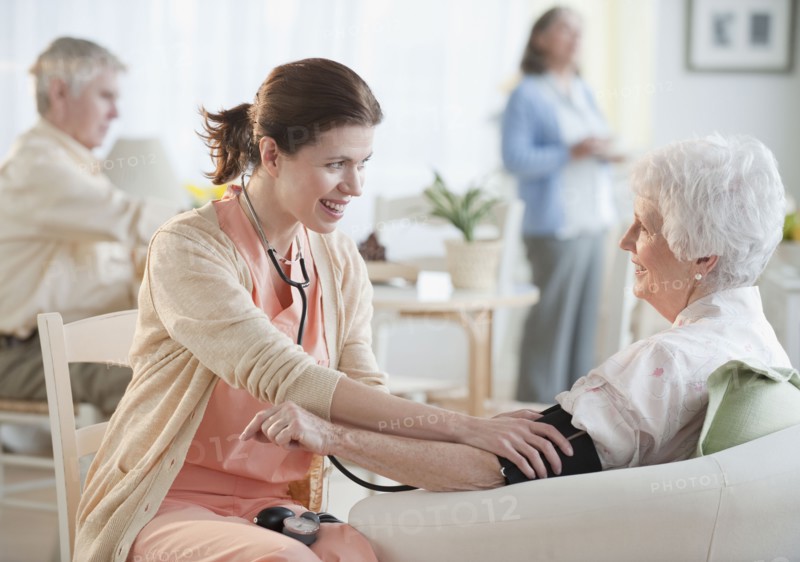 Nurse taking senior woman’s blood pressure.