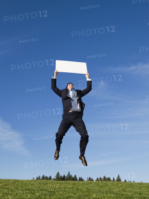 Businessman jumping with blank sign.