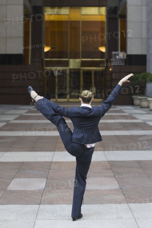 Businesswoman dancing in urban setting. Photographe : PT Images
