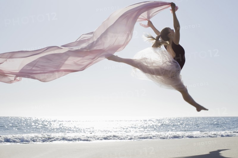 Dancer leaping on beach. Photographe : PT Images