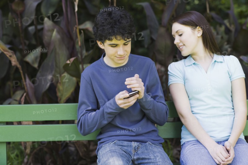 Young couple sitting on park bench. Photographe : PT Images