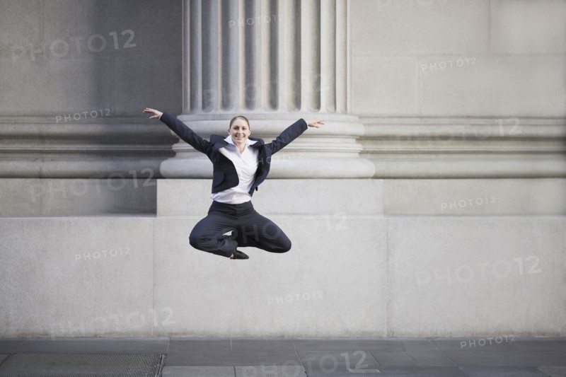 Businesswoman dancing in urban setting. Photographe : PT Images