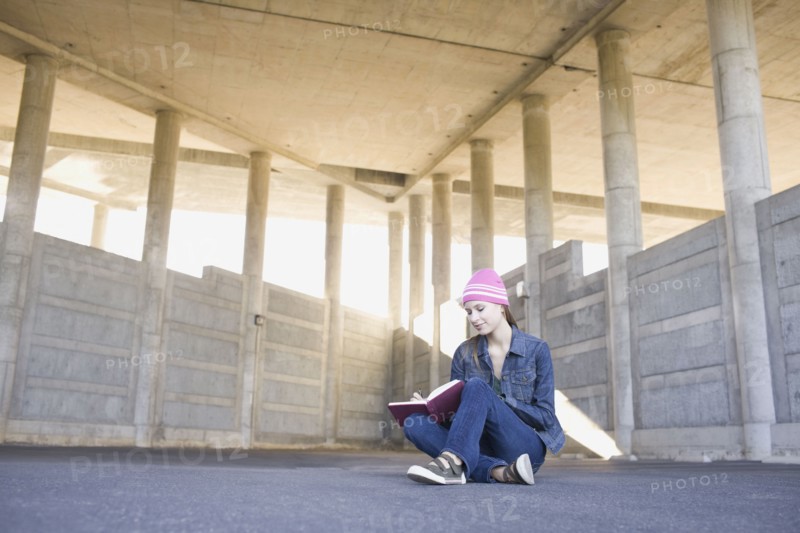 Young woman reading in urban setting. Photographe : PT Images