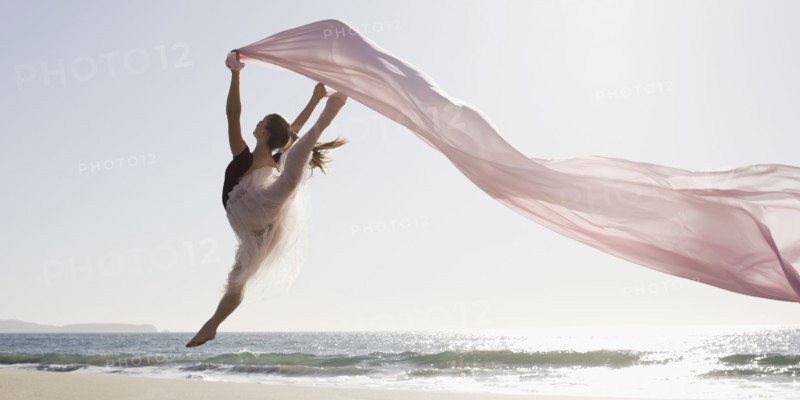 Dancer leaping on beach. Photographe : PT Images