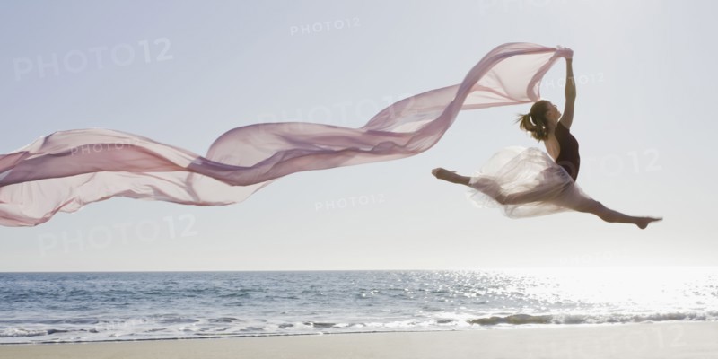Dancer leaping on beach. Photographe : PT Images