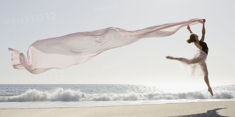 Dancer leaping on beach. Photographe : PT Images