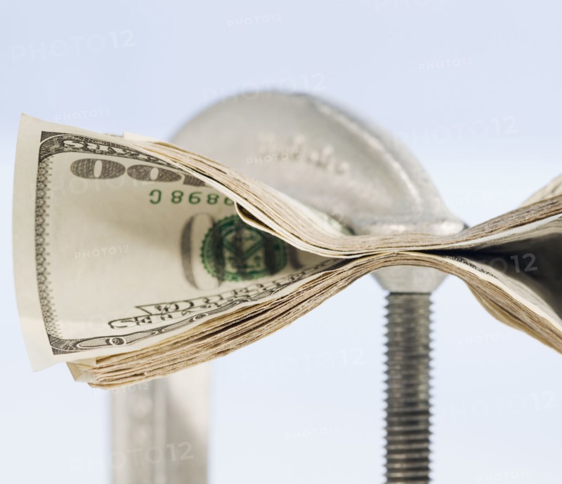 Paper currency squeezed in C clamp. Photographe : Jamie Grill