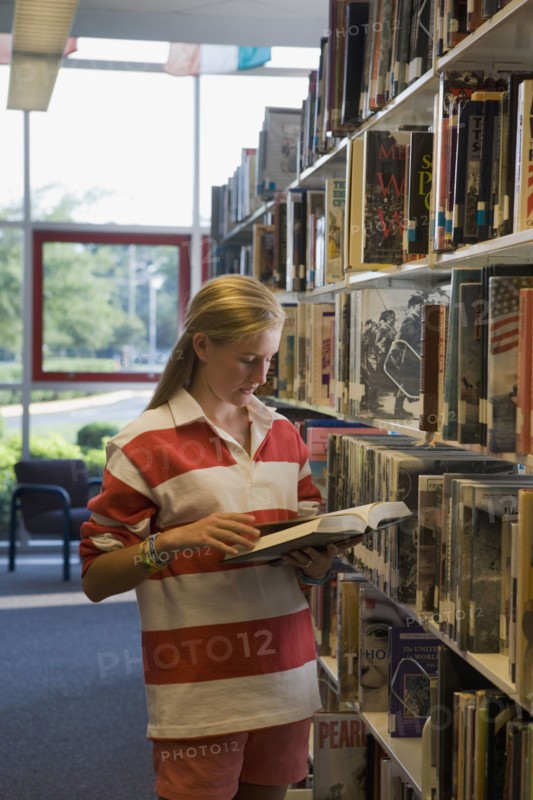 Girl reading book in library. Photographe : mark edward atkinson