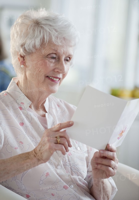 Senior woman reading greeting card.