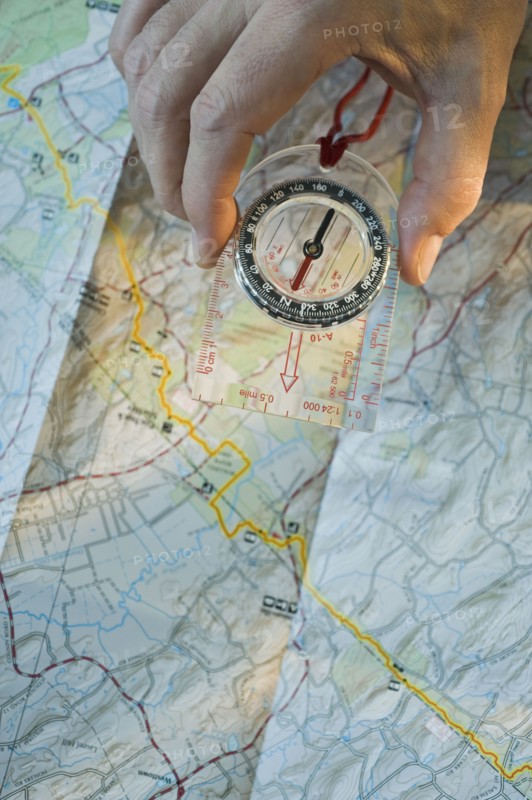 Man holding compass over map.