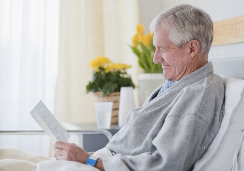 Senior man reading get well card in hospital.