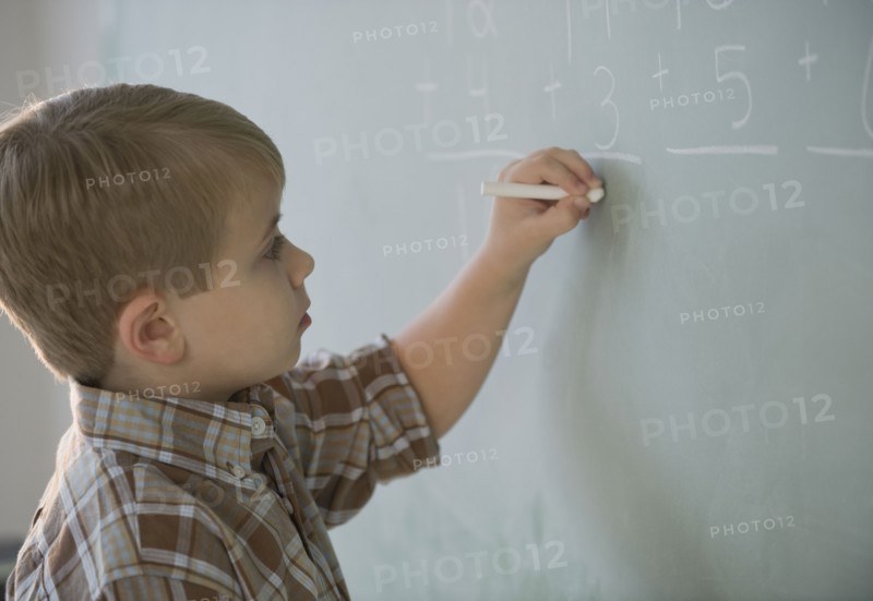 Boy doing math on blackboard.