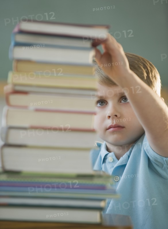 Boy taking book from stack.