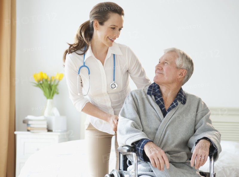 Nurse helping senior man in wheelchair.