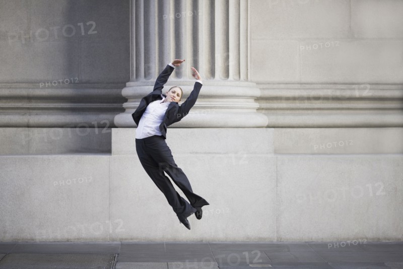 Businesswoman dancing in urban setting. Photographe : PT Images