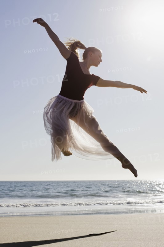 Dancer leaping on beach. Photographe : PT Images