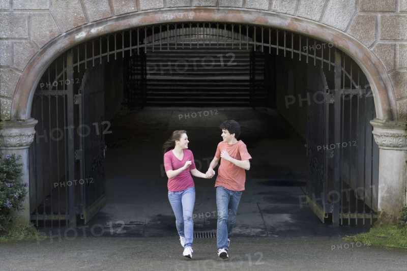 Young couple running through tunnel. Photographe : PT Images