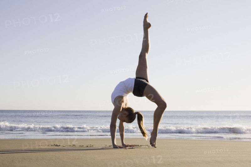 Woman doing yoga on beach. Photographe : PT Images