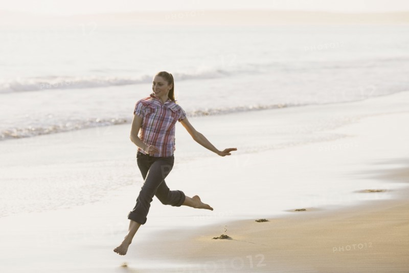 Woman running on beach. Photographe : PT Images