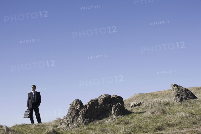 Businessman standing on remote hill. Photographe : PT Images