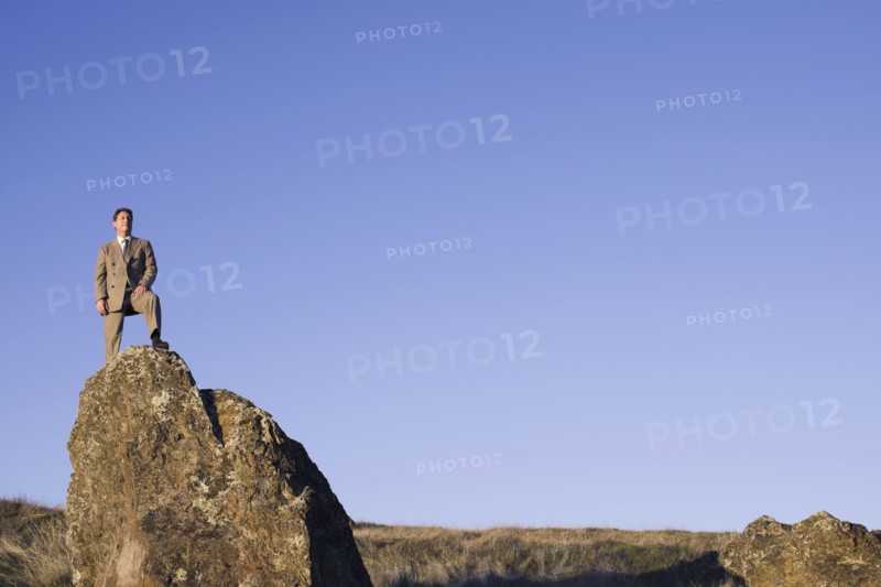 Businessman standing on rock. Photographe : PT Images