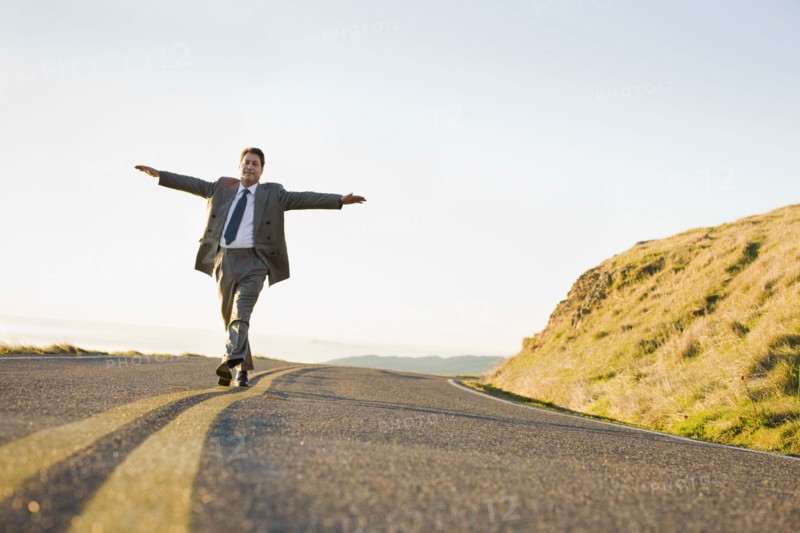 Businessman running on remote road. Photographe : PT Images