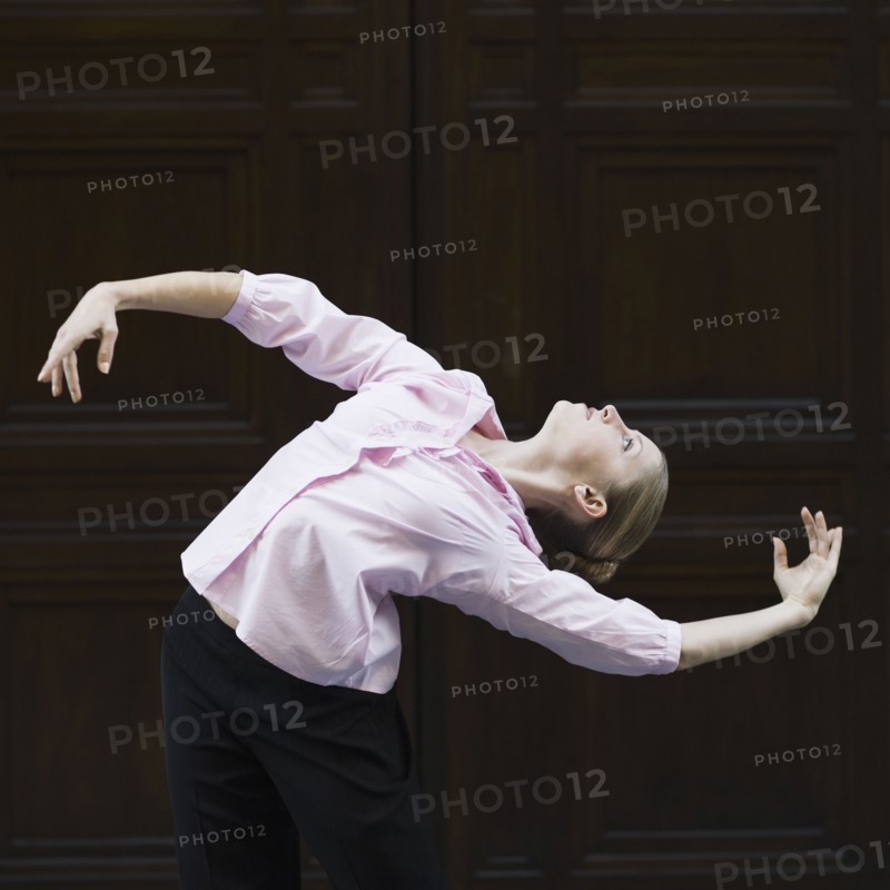 Businesswoman dancing in urban setting. Photographe : PT Images