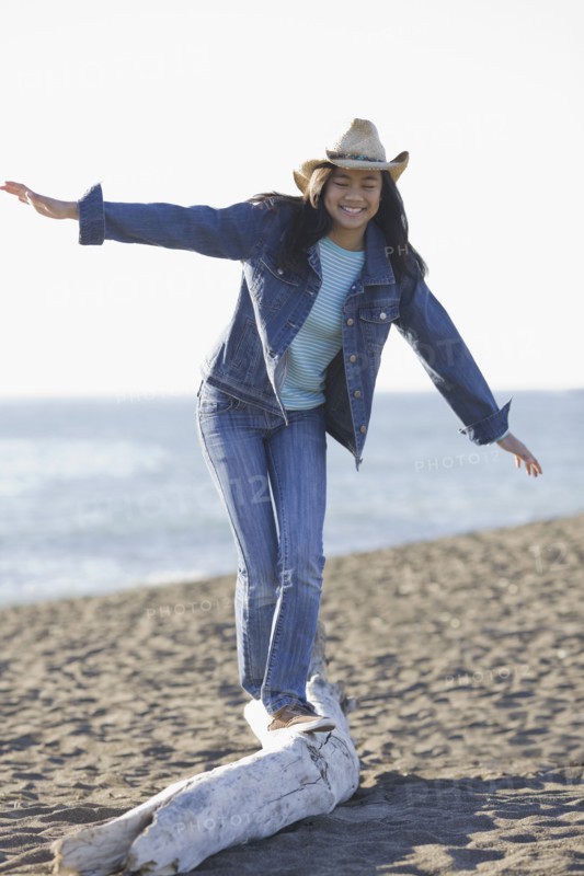 Teenage girl balancing on driftwood. Photographe : PT Images