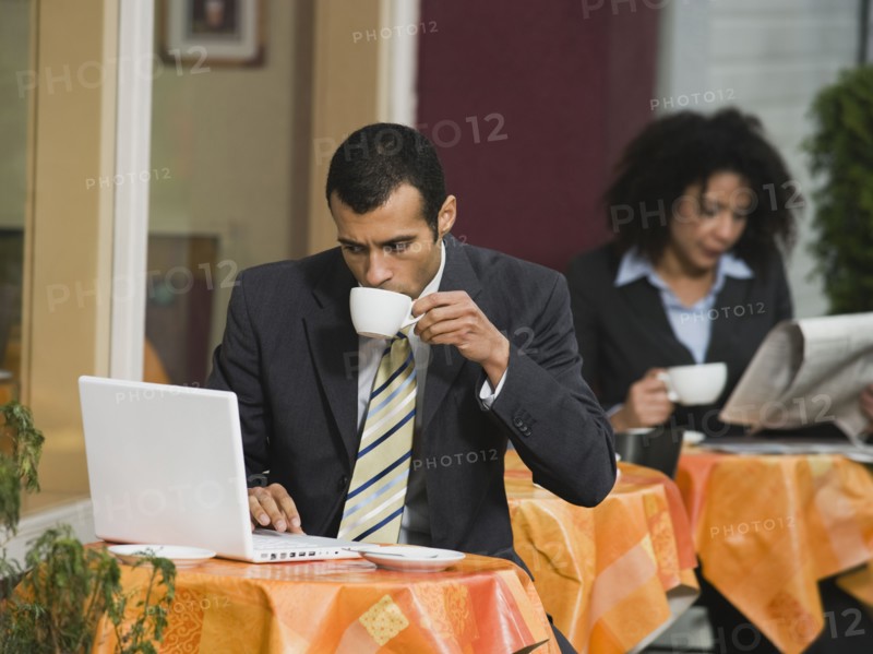 Businessman looking at laptop at outdoor cafe.