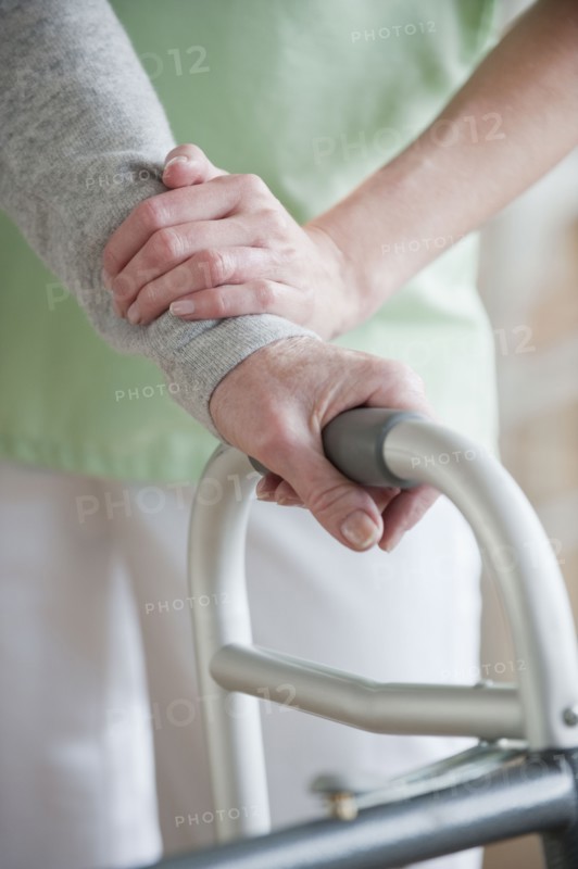 Nurse helping senior woman in walker.