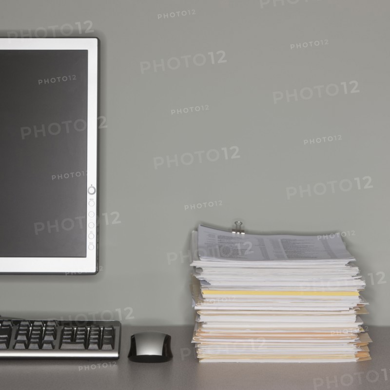 Computer and stack of paperwork.
