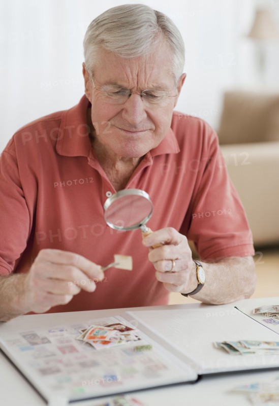 Senior man looking at stamp collection.