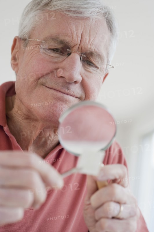 Senior man looking at stamp collection.