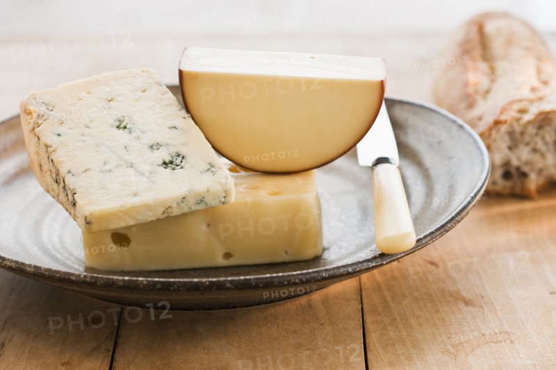 Pieces of cheese with grapes on background.
