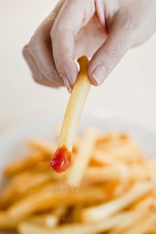 Woman with french fries, close-up of hand.