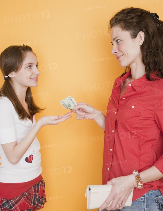Mother giving daughter (10-12 years) pocket money. Photographe : Jamie Grill